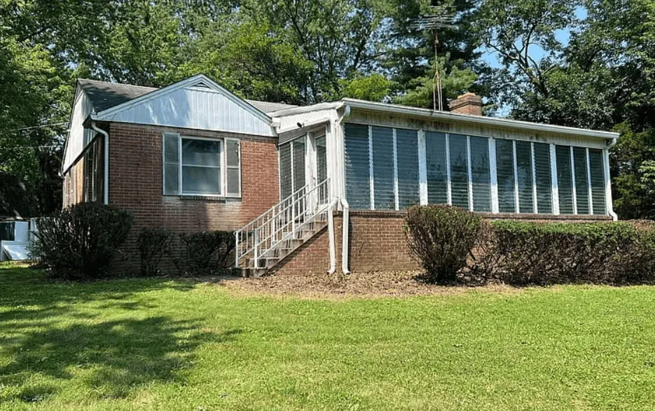 Exterior view of a modest community center building with a parking area and green lawn.
