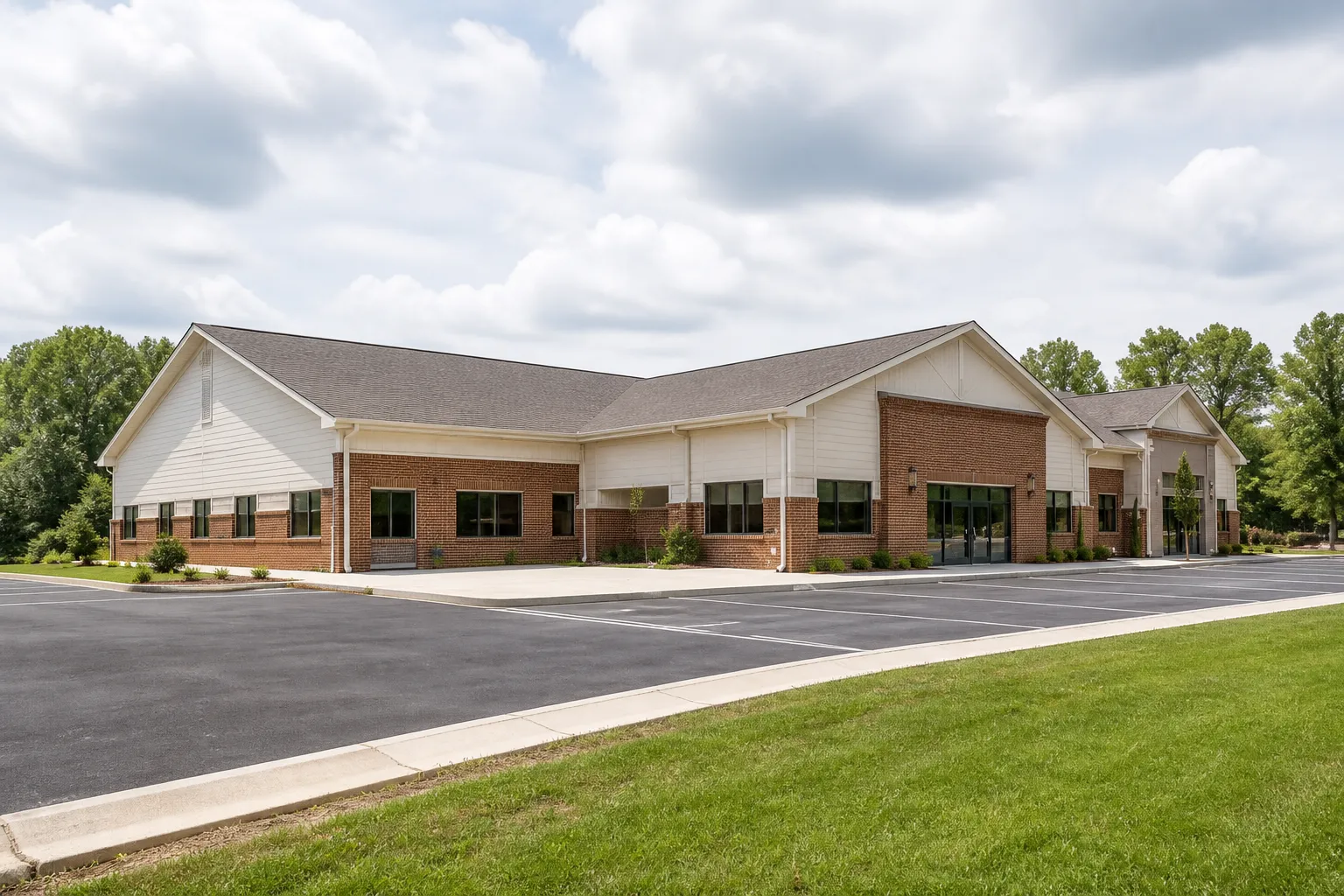 Exterior view of a modest community center building with a parking area and green lawn.